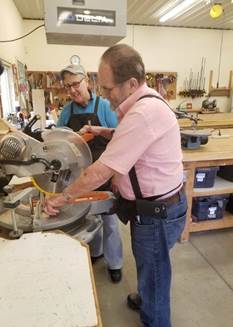 Hobby Shop volunteer, Susan, assists participant, John, with a woodworking project.